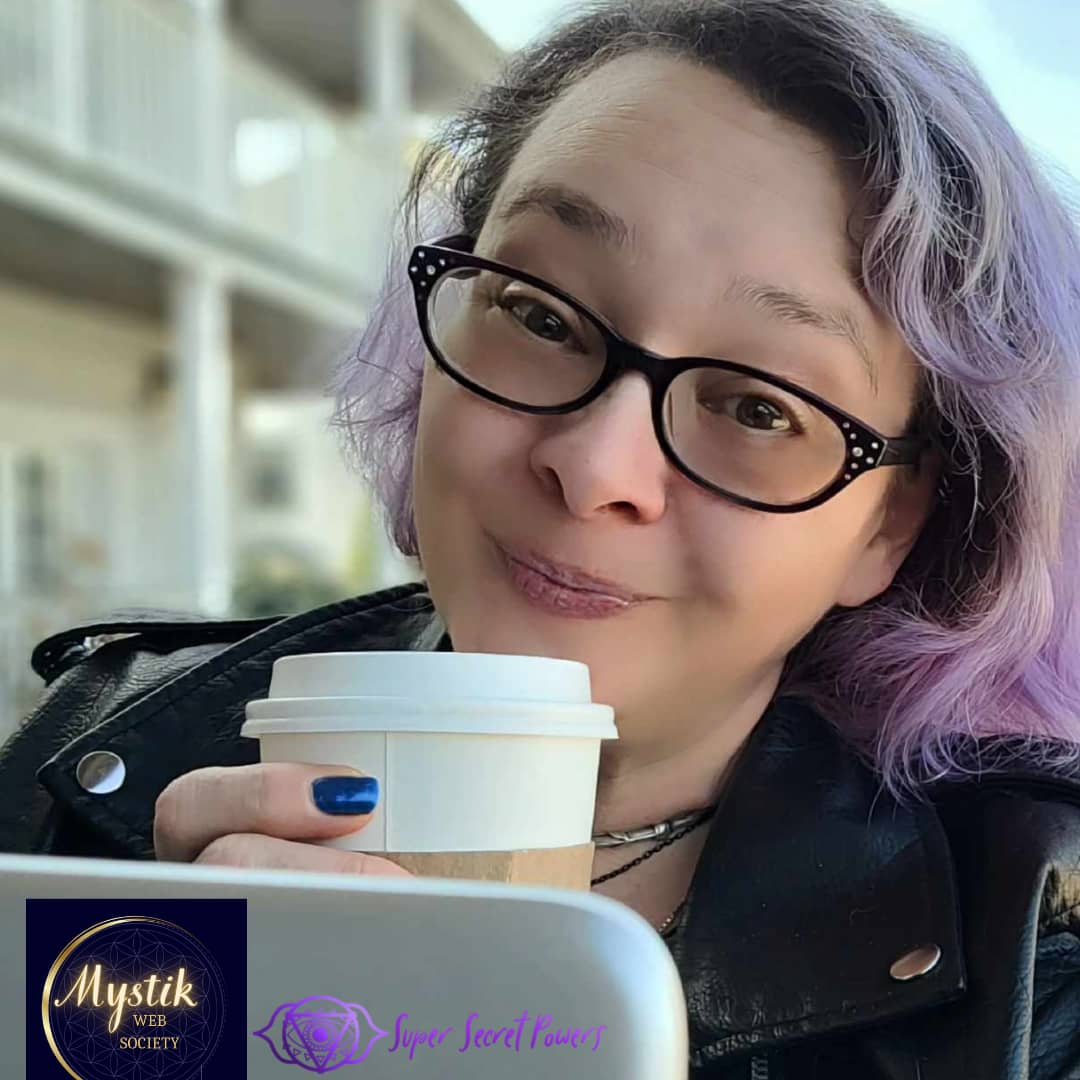 Lindsay Baldassano, a spiritual entrepreneur, at a cafe with a mocha and her laptop, working on her website. She the founder of the Mystik Web Society for spiritual small business owners, like tarot readers, reiki healers, and other types of metaphysical practitioners who need to learn the tech and strategy to make their web presence shine and make profit.